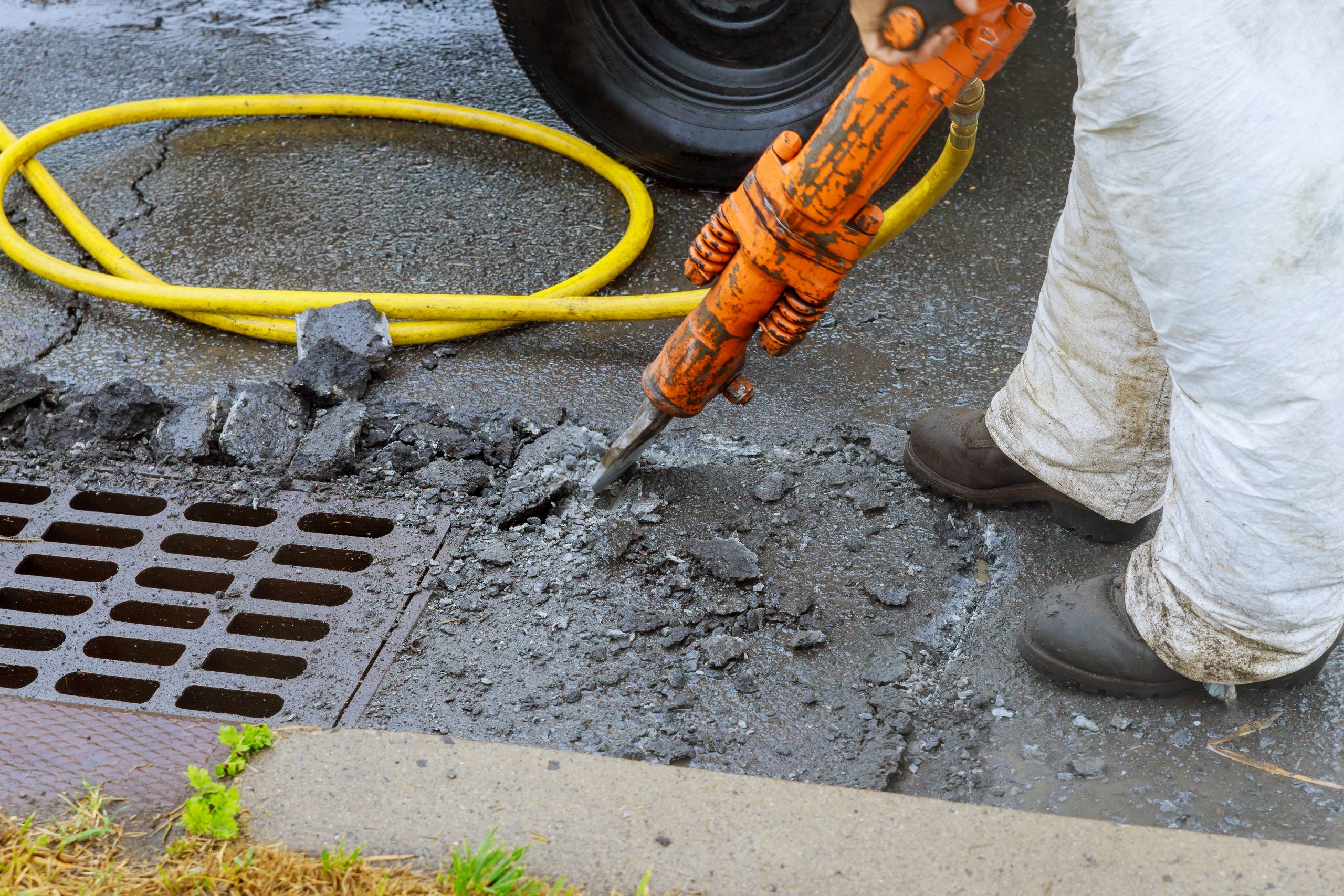 Jackhammer with a pneumatic drill perforating the asphalt of an urban road being renovated on a street construction