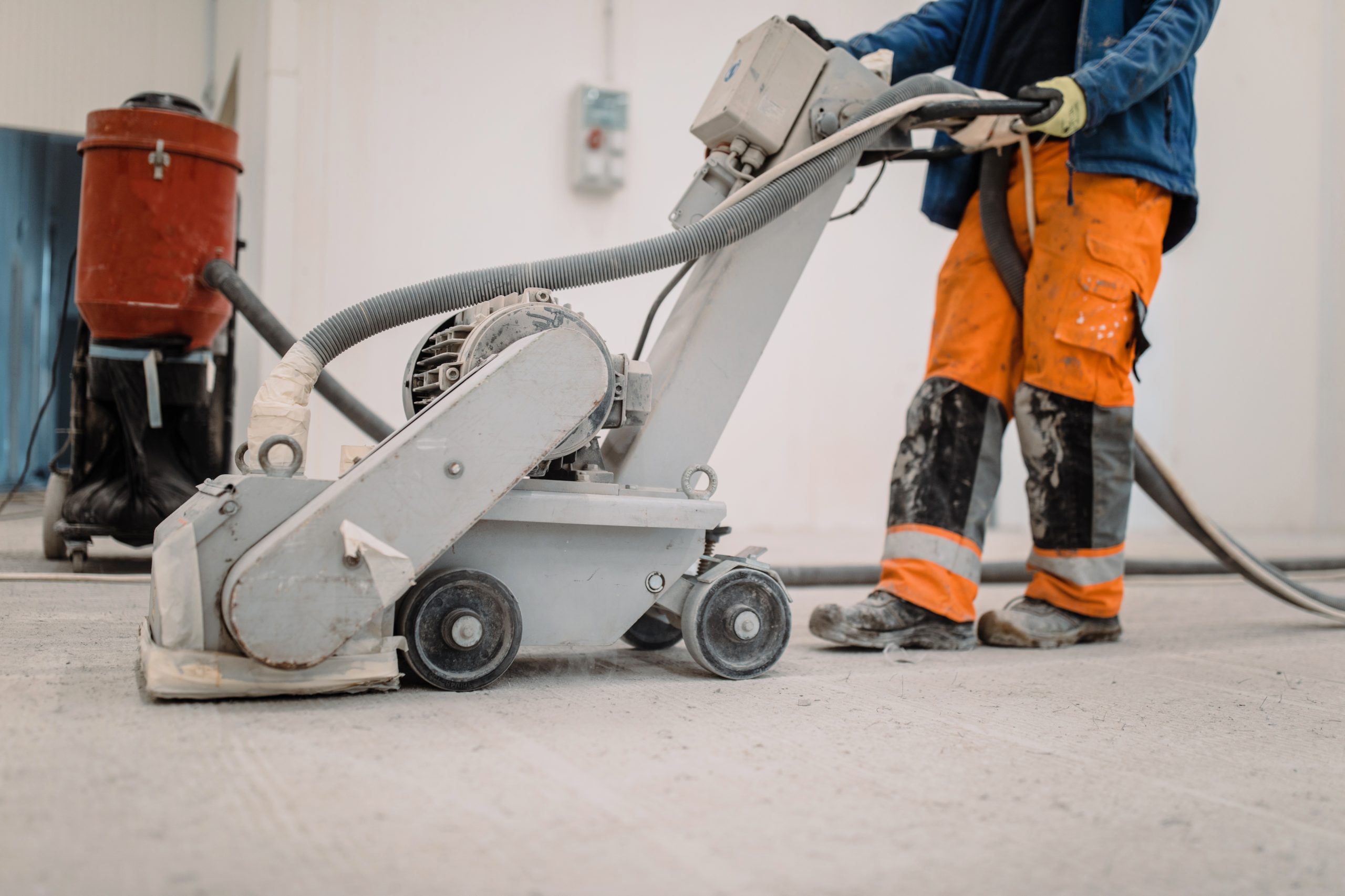 Workers grind the concrete floor at the construction site. Prepares the floor for polyurethane mortar